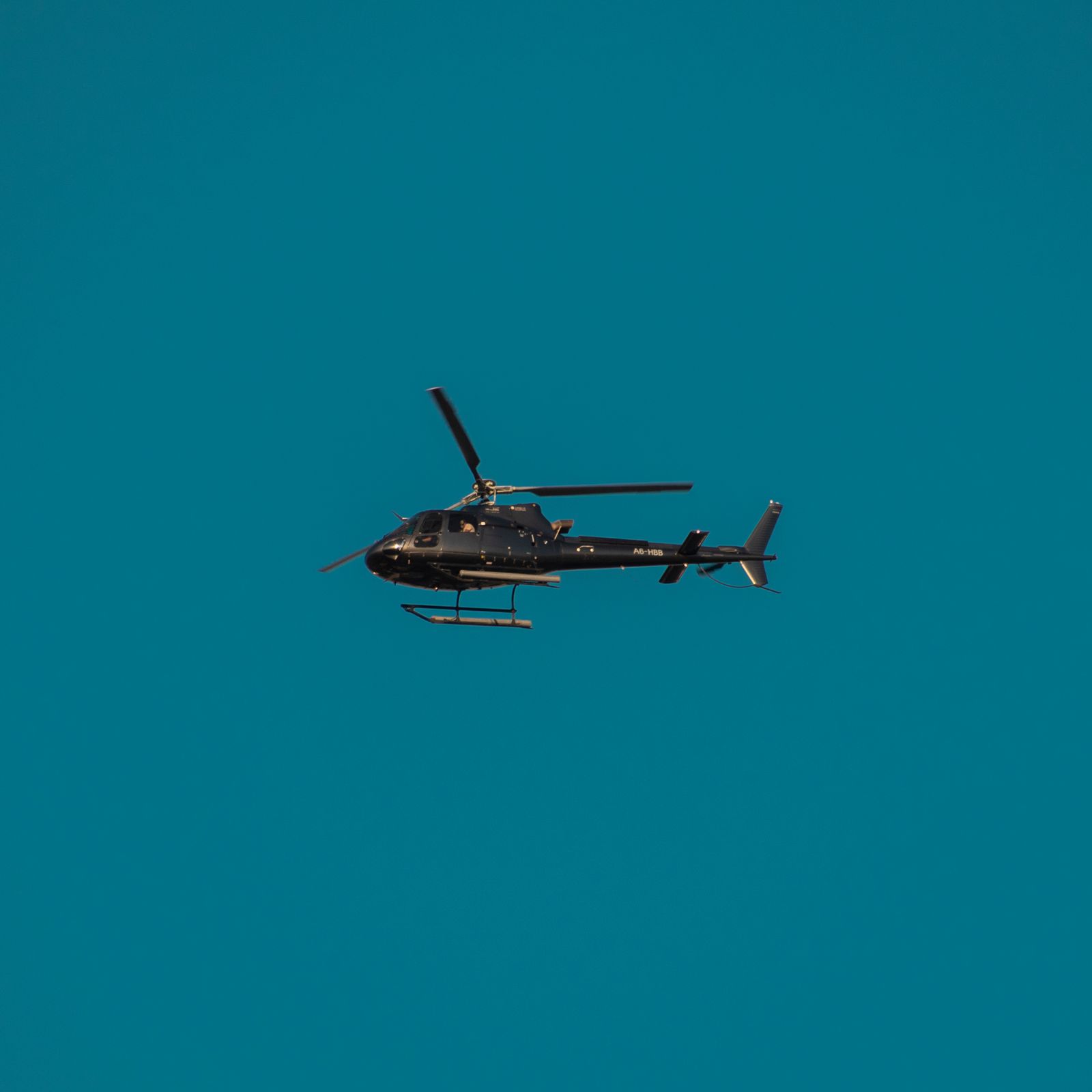 Black tour helicopter in flight over Dubai, UAE