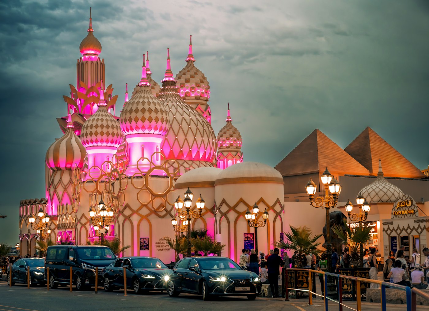 Fantasy architecture with pink and gold domes illuminated at dusk at Global Village Dubai