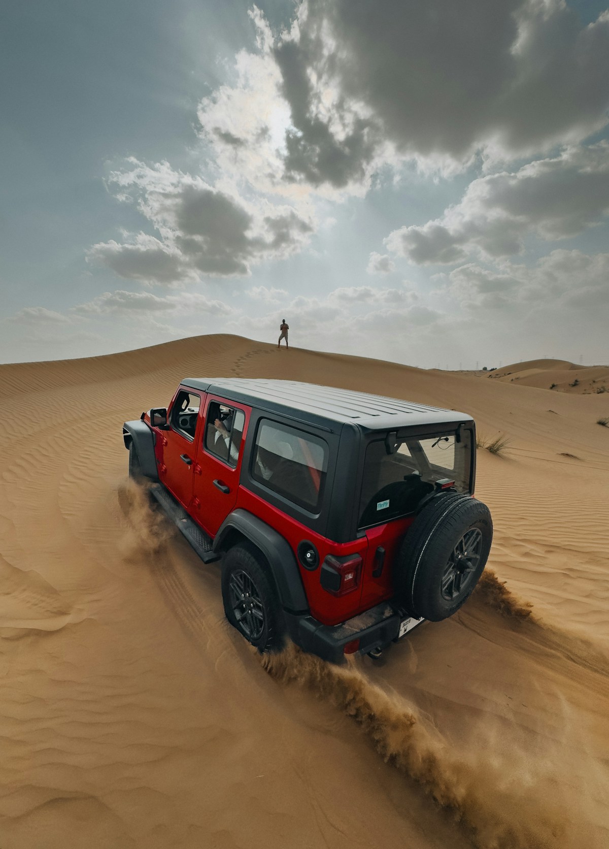 Red 4WD vehicle driving through the desert near Hatta mountains, Dubai UAE