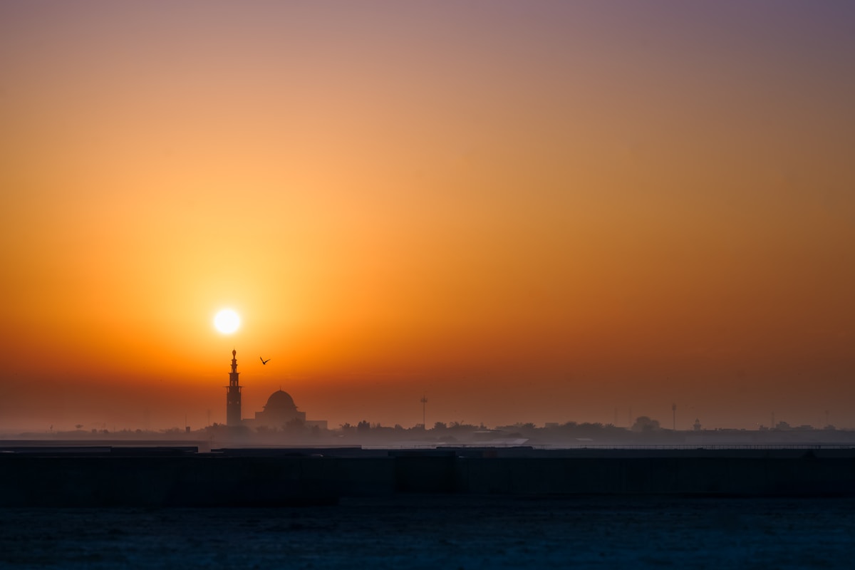 Ajman city skyline at sunset with warm orange sky, UAE