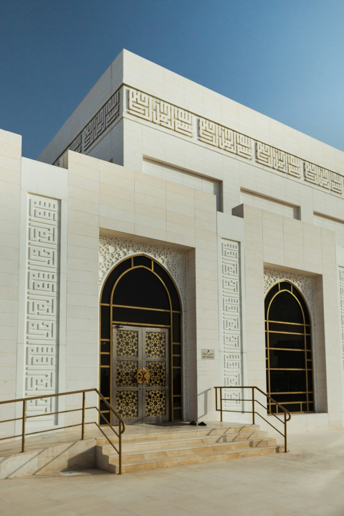 White concrete mosque with arch doorways in Ajman, UAE