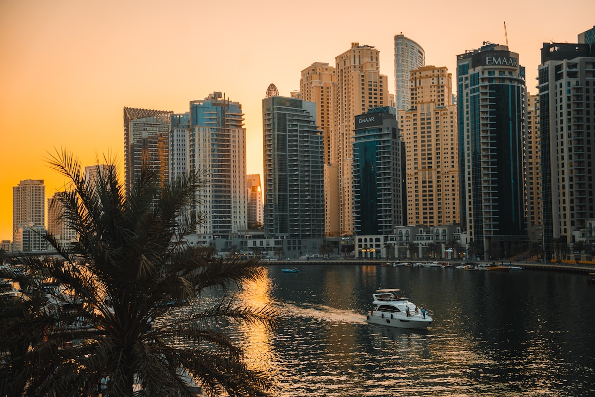 Boat sailing past Dubai Marina skyscrapers at sunset, UAE