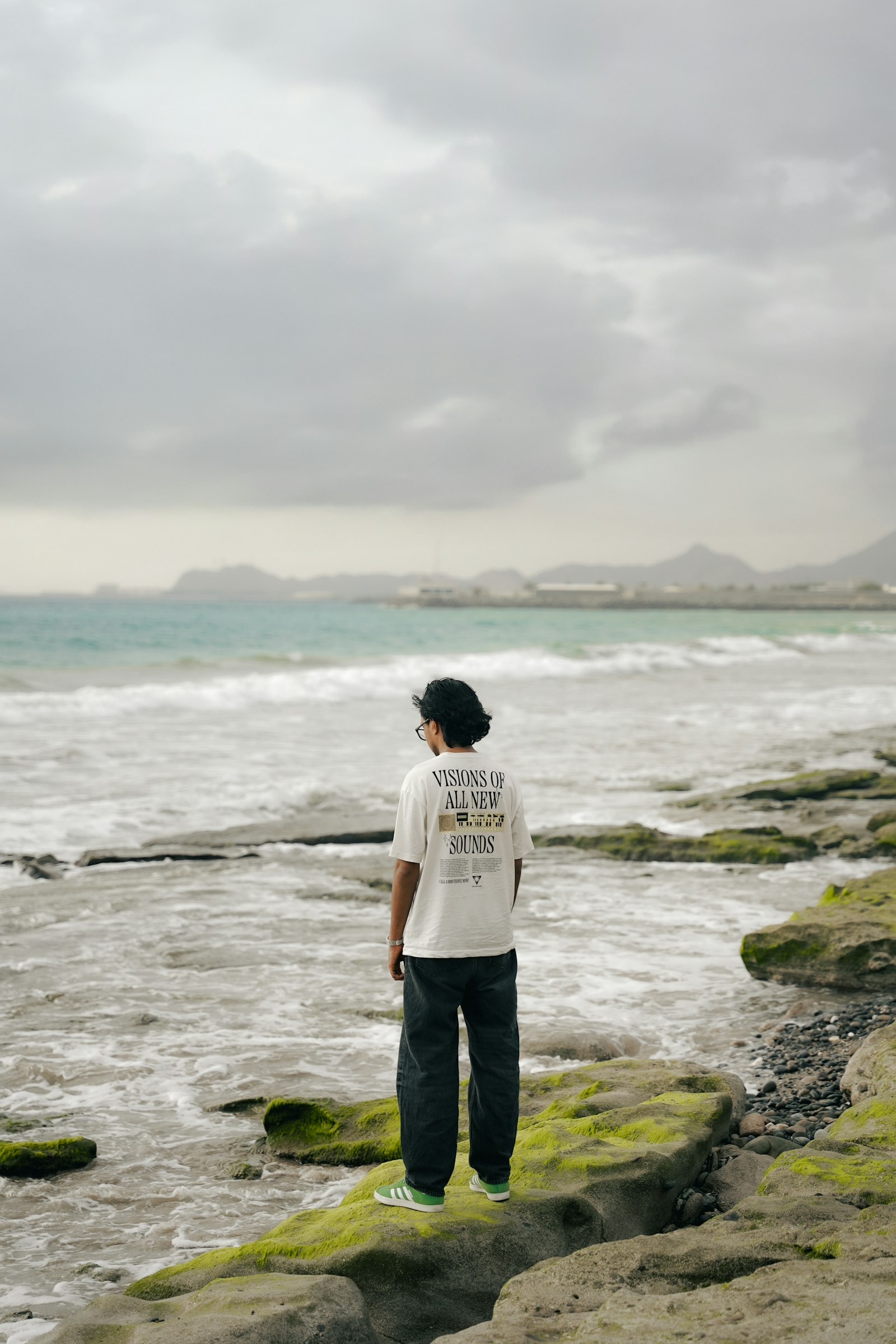 Person standing on rocky east coast shoreline in Fujairah UAE with turquoise sea