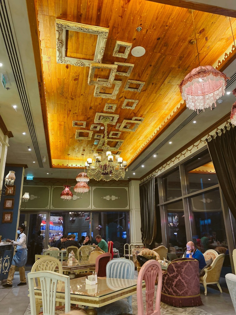 Ornate restaurant interior with carved wooden ceiling and chandeliers in Sharjah UAE