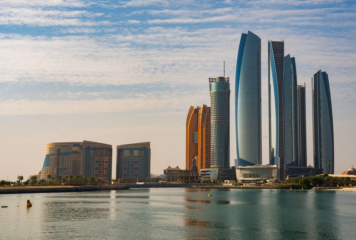 Abu Dhabi Etihad Towers skyline reflected across the water at sunrise, UAE