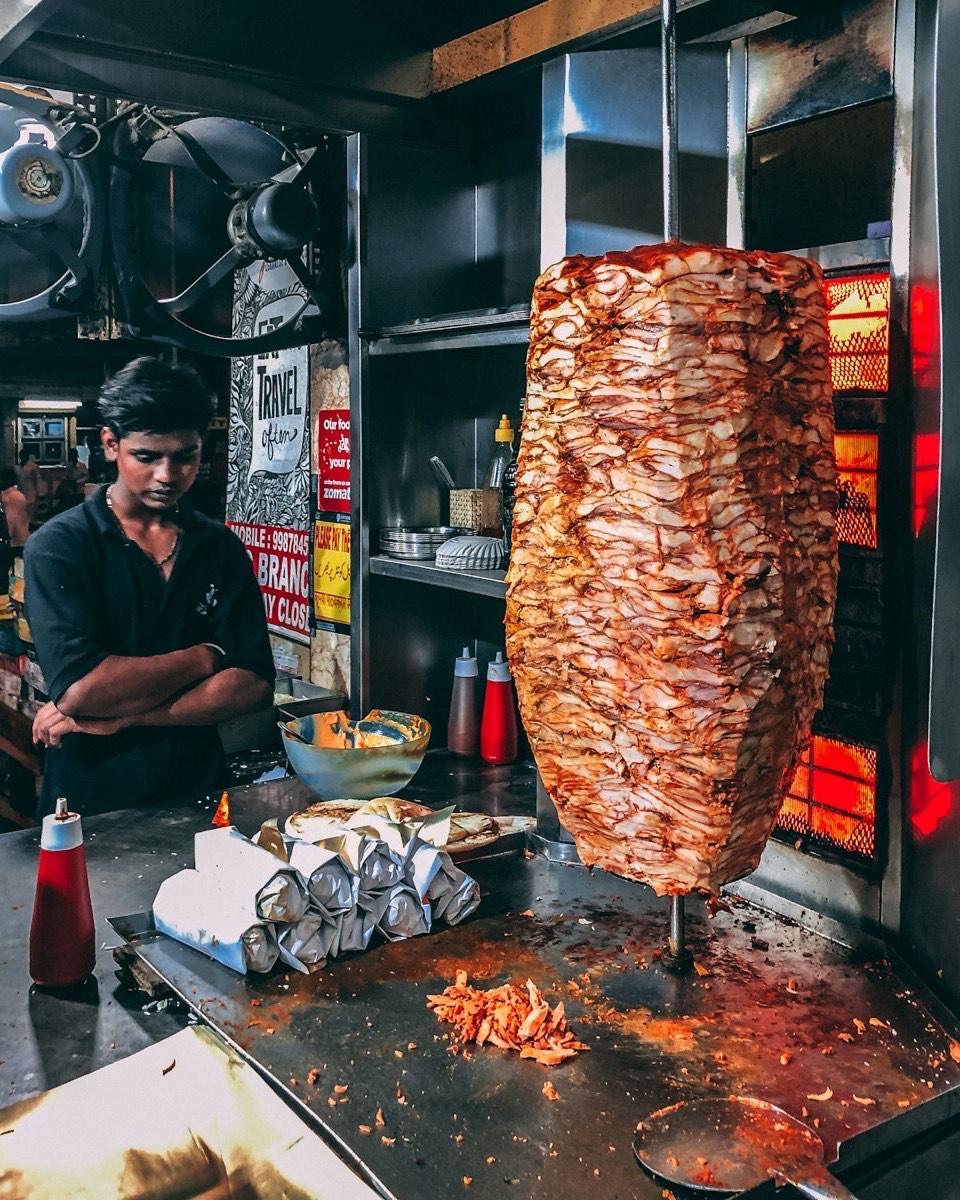 Man standing in front of a shawarma grill and food display Dubai UAE