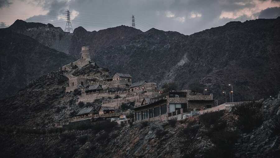 Old stone fort on a rocky hillside above Fujairah with Hajar Mountains behind