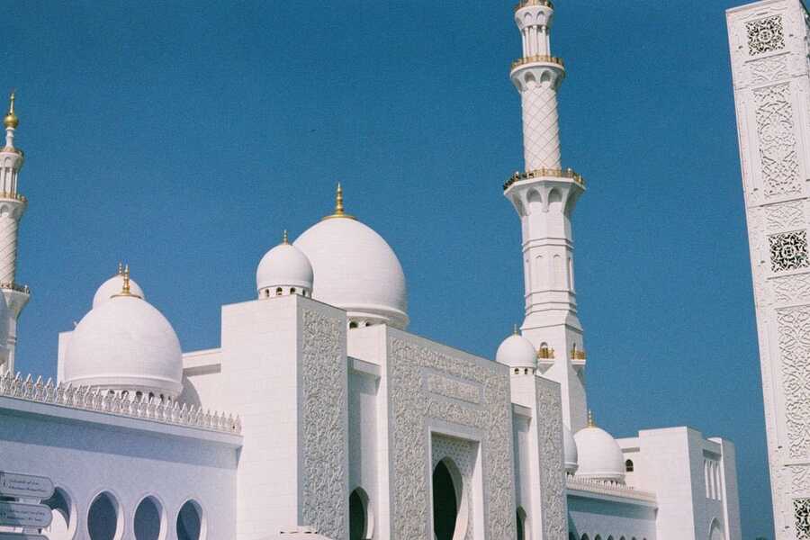 White domes and minarets of Sheikh Zayed Grand Mosque under a blue sky