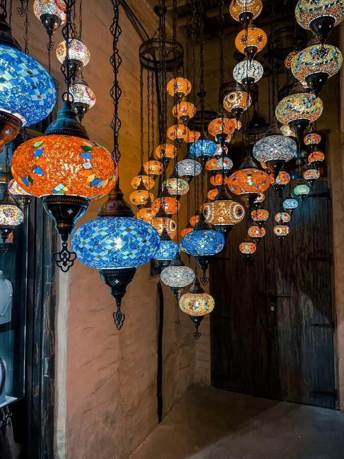 Hanging mosaic lanterns in orange and blue inside a Dubai souk