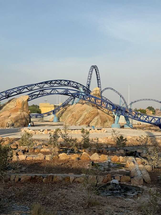 Blue steel roller coaster track over rocky scenery at Warner Bros. World Abu Dhabi