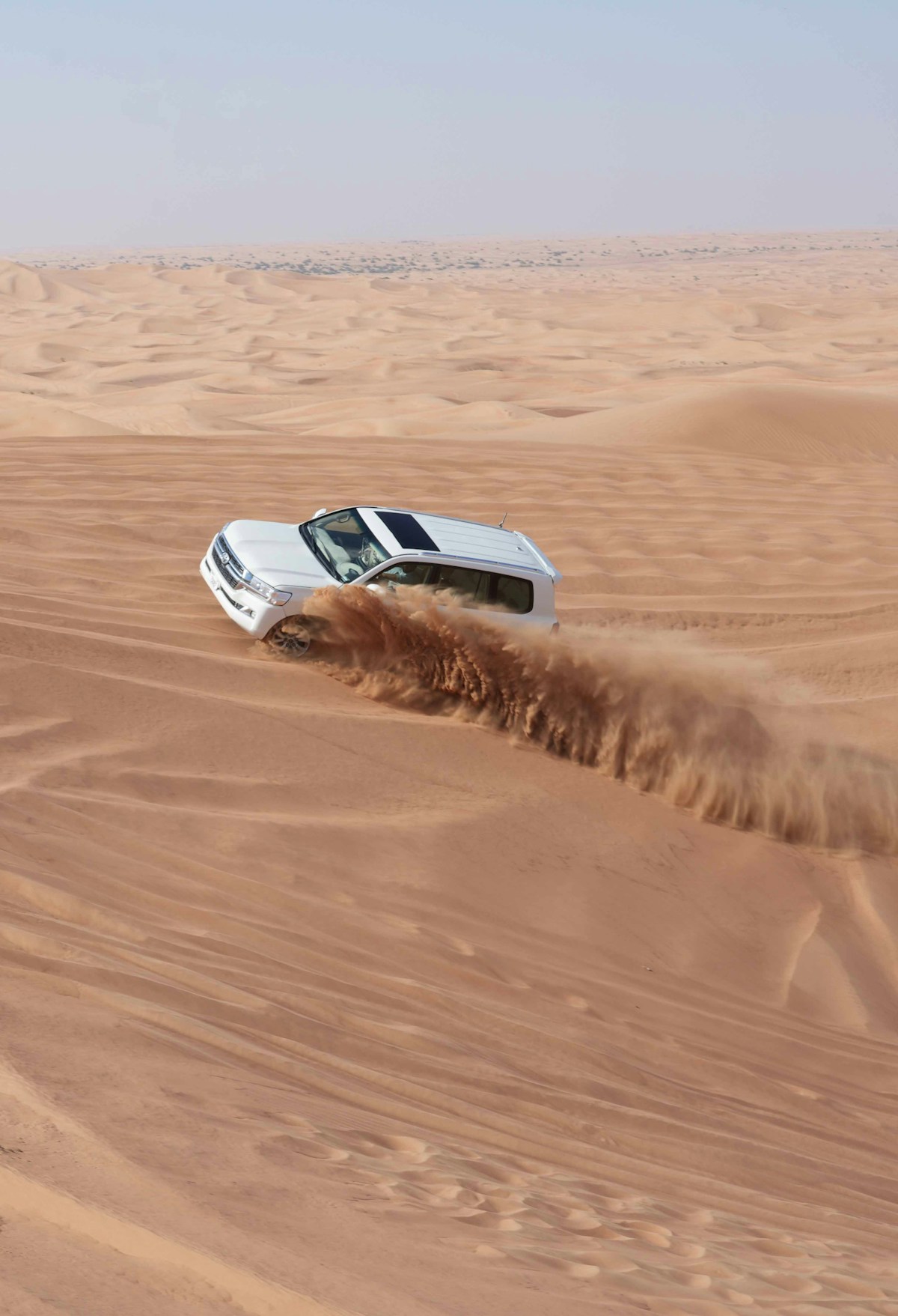 Car driving through desert sand on UAE road trip