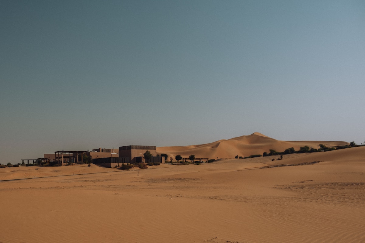 Desert resort buildings set against large sand dunes in Liwa, Abu Dhabi UAE