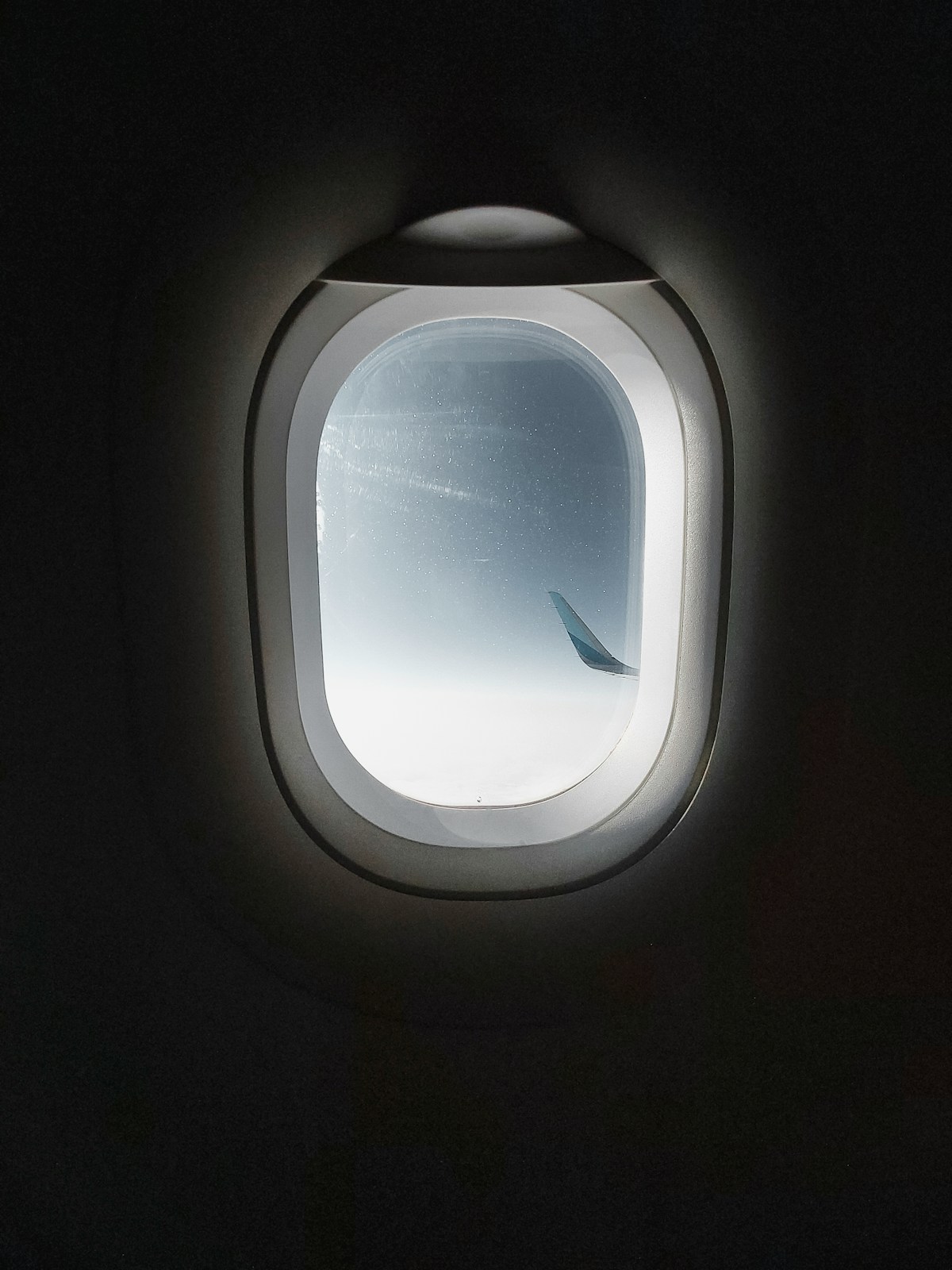 Airplane window with sky view during flight, travel to Abu Dhabi UAE