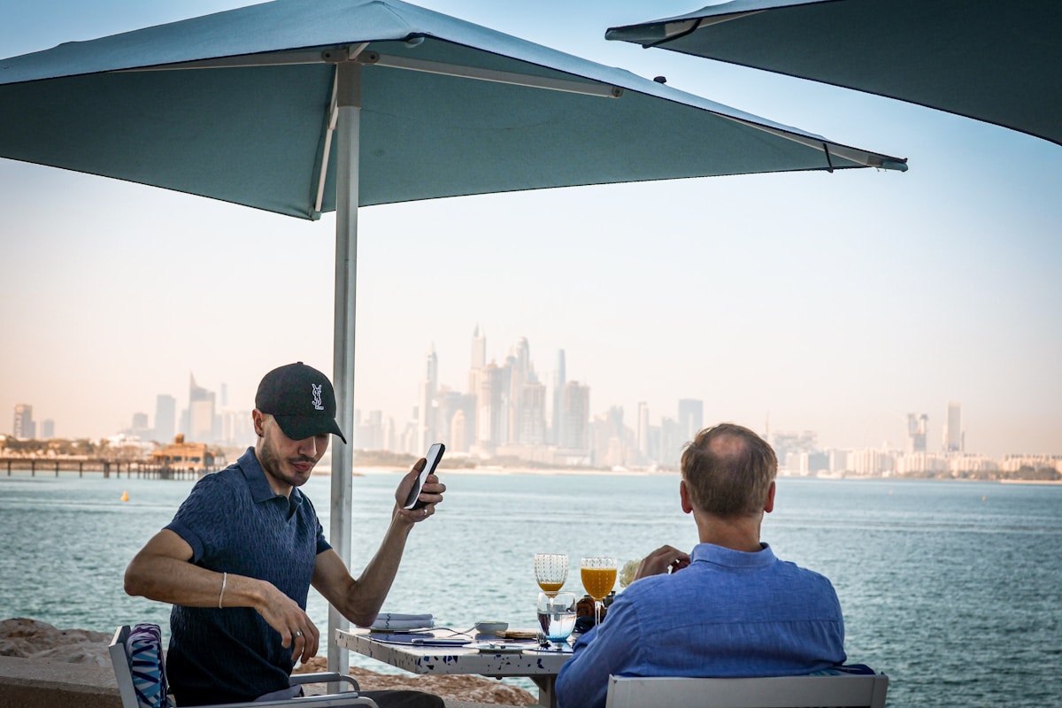 Two men dining outdoors on a terrace with Dubai skyline view, UAE