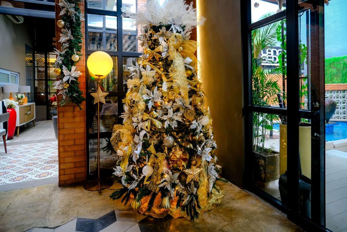 Elegantly decorated Christmas tree with gold and white ornaments in a luxury hotel lobby, festive season Dubai UAE