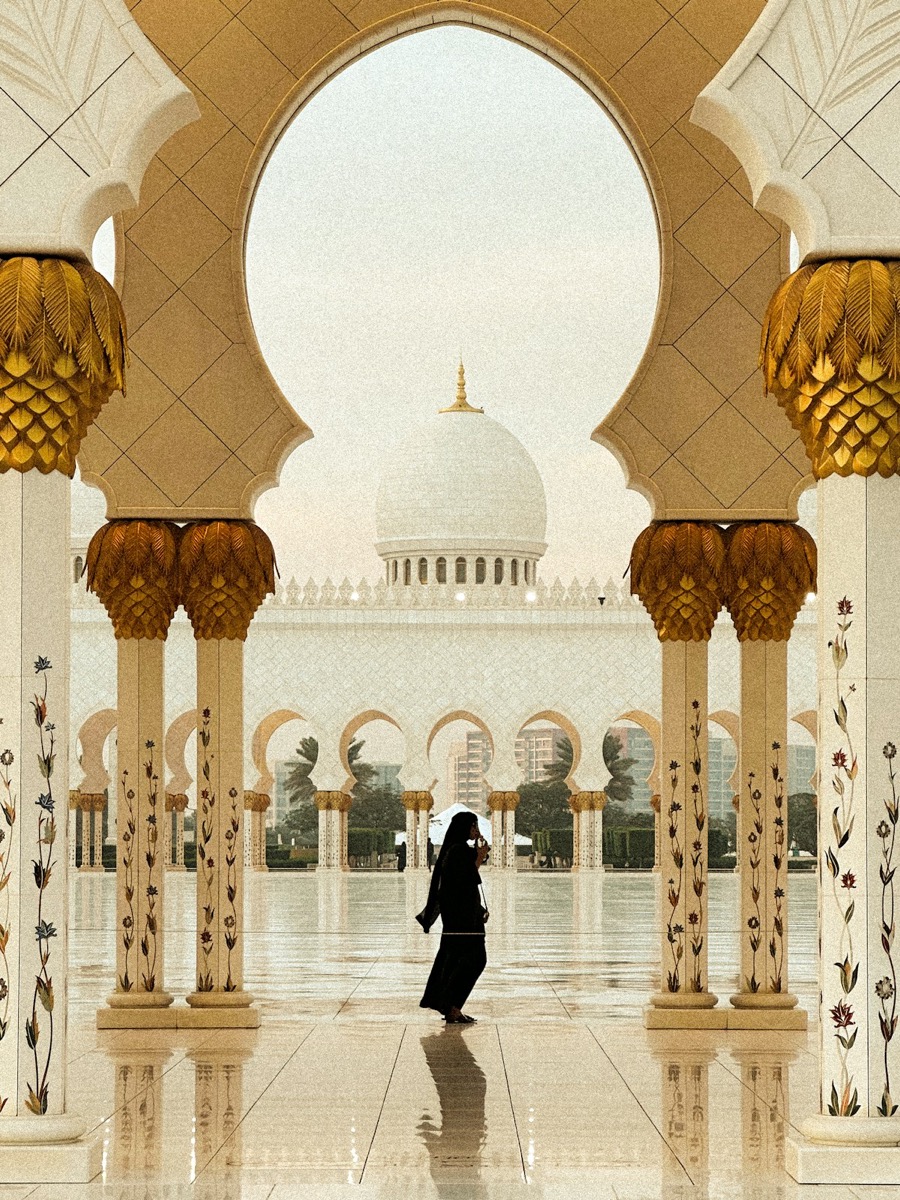 Woman walking through a grand mosque courtyard in Abu Dhabi UAE