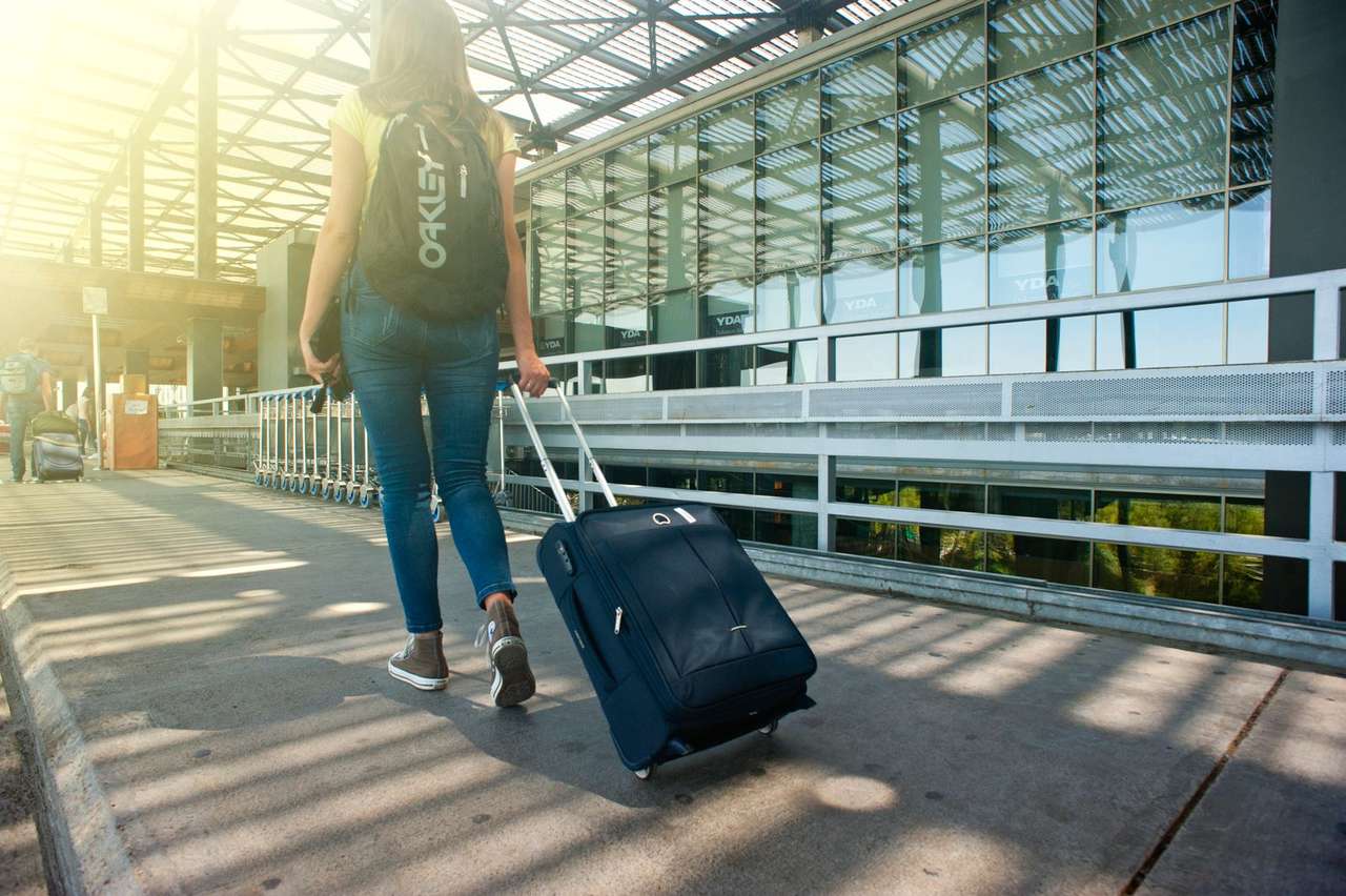 Traveller with suitcase walking into a modern airport terminal, Dubai International Airport DXB UAE