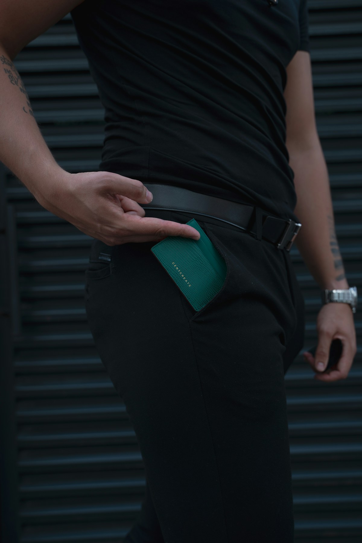 Person tucking a green leather wallet into their back pocket in Dubai, UAE