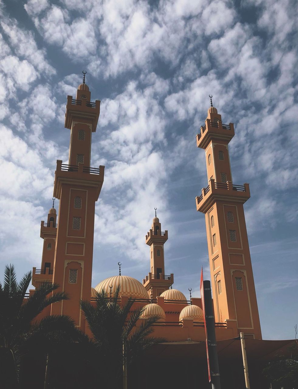 UAE mosque with four minarets and golden domes against a dramatic cloudy sky