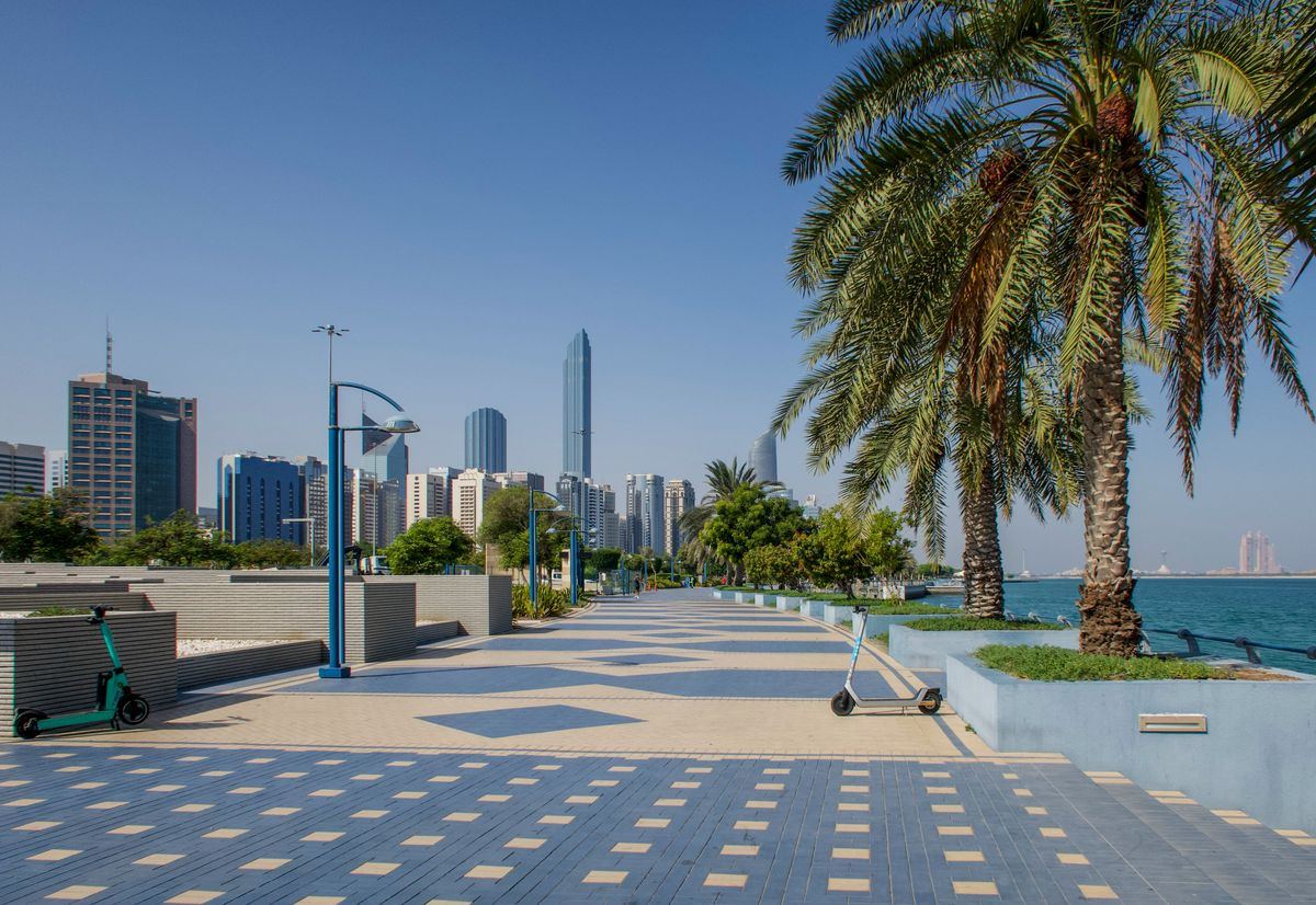 Palm-lined Corniche promenade with Abu Dhabi skyline in the distance