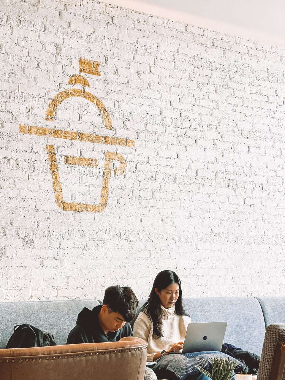 Two people working on laptops in a bright cafe