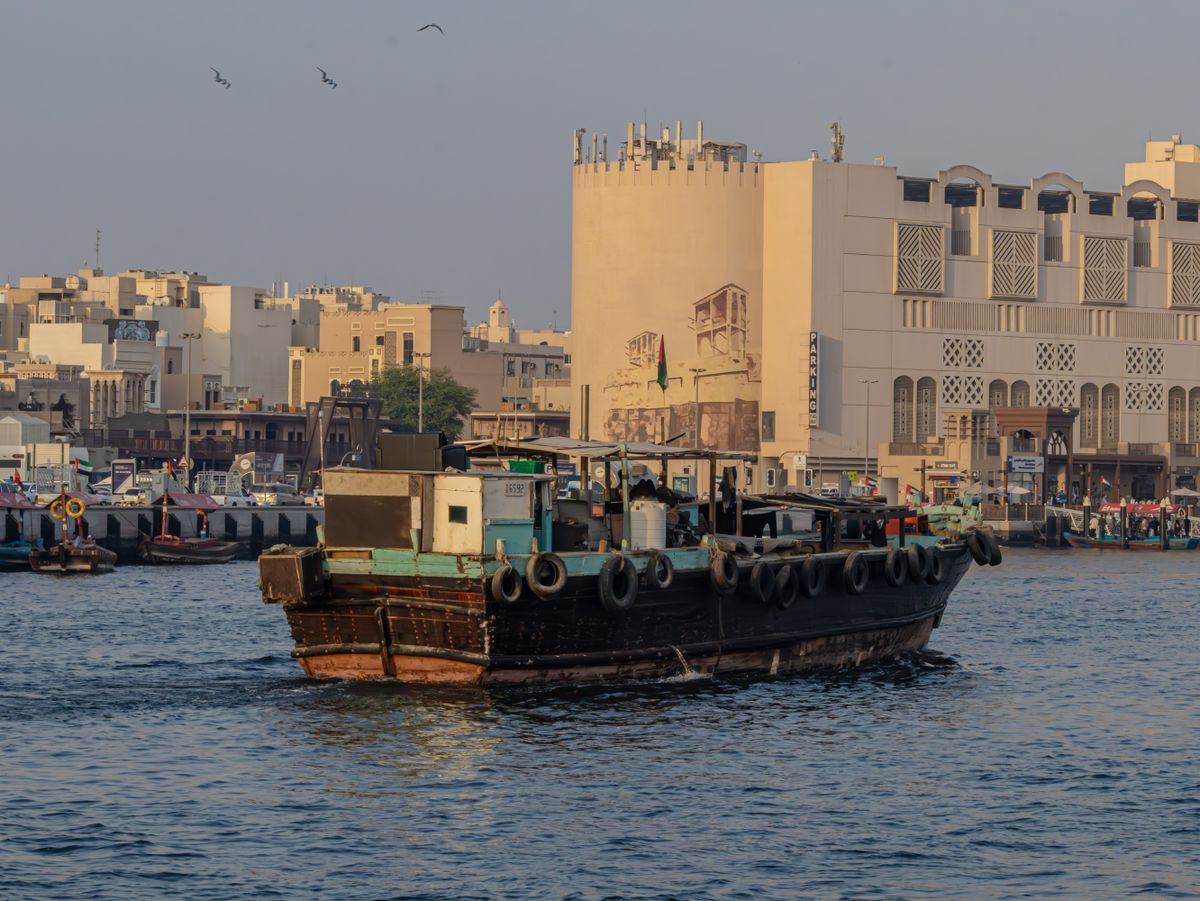 Traditional wooden boat on Dubai Creek with old buildings behind