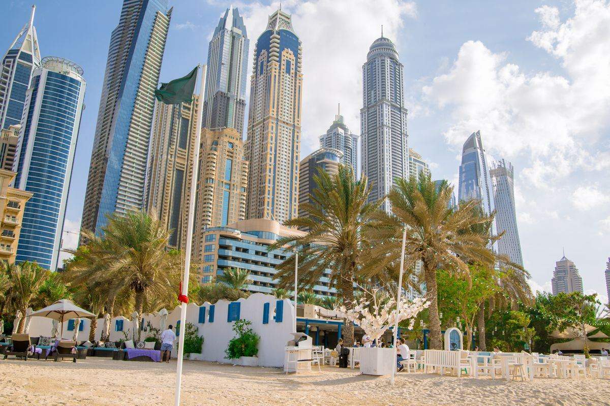 Dubai Marina towers above a sandy beach with palm trees