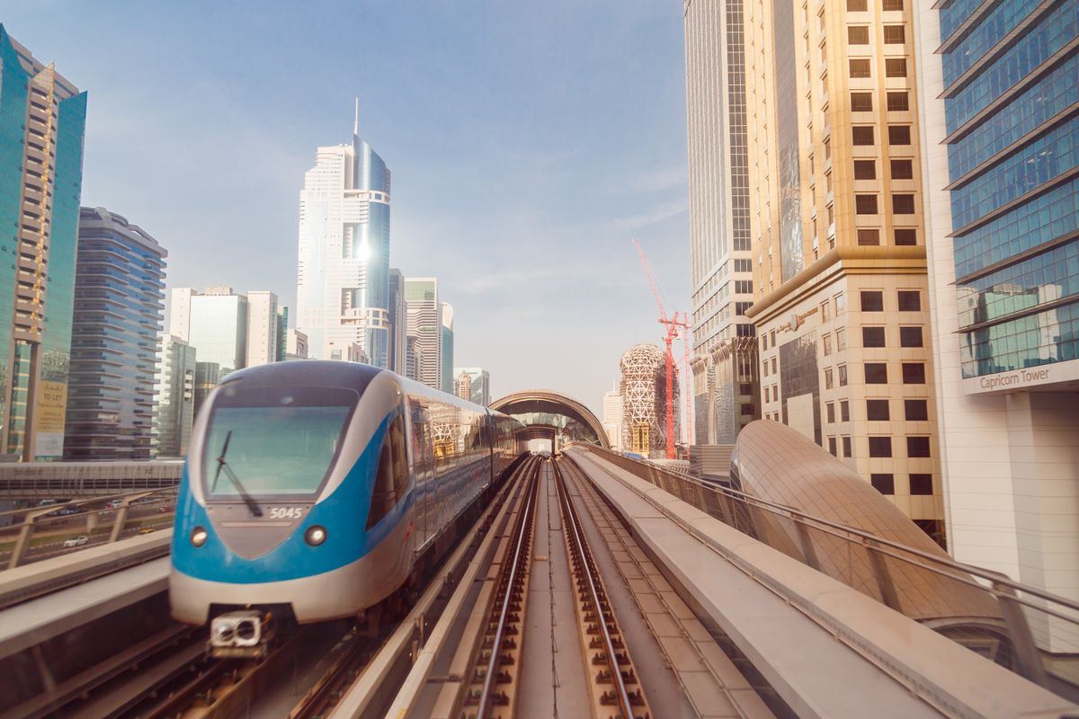 Dubai Metro train on elevated track between skyscrapers
