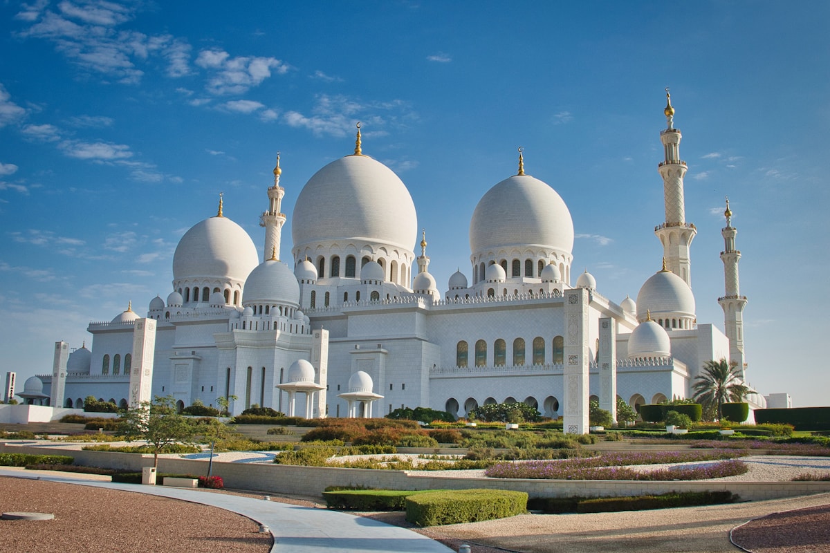 Grand white mosque with domes and minarets under blue sky Abu Dhabi UAE