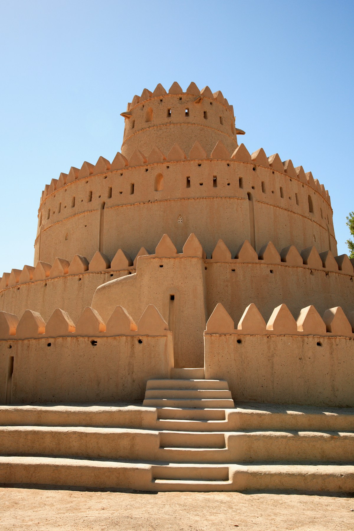 Ancient mud-brick round fort tower under a clear blue sky in Al Ain, United Arab Emirates