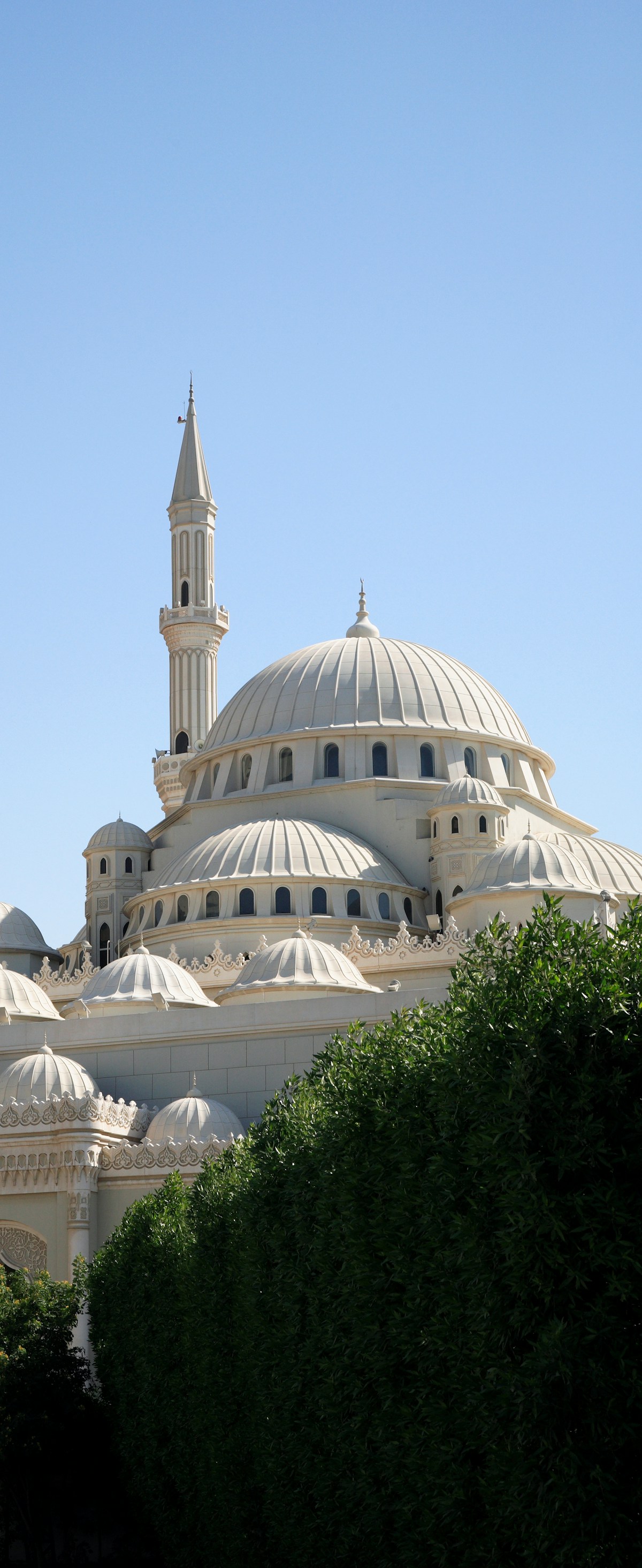 Grand white mosque with dome and minaret rising above Sharjah, United Arab Emirates